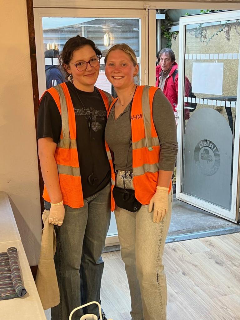 Two students serving meals in orange vests