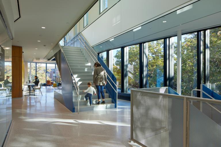 Light filled building with a mother and child walking up a set of stairs