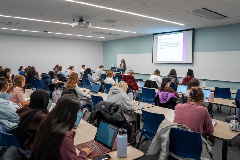 Classroom full of college students with a lecturer at front of the room