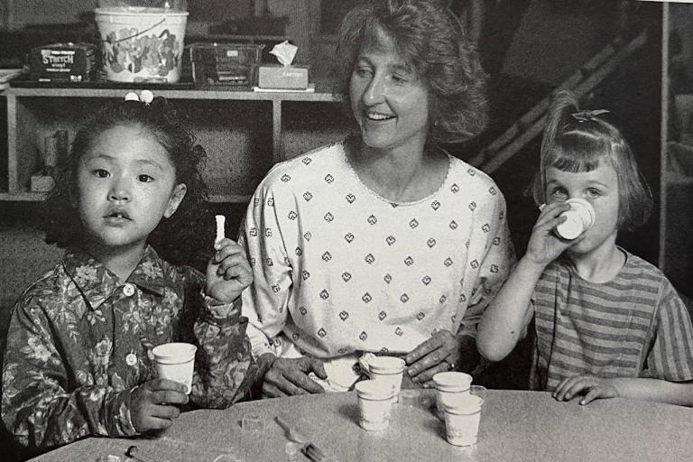Megan Gunnar sitting at a table with two young children drinking out of cups