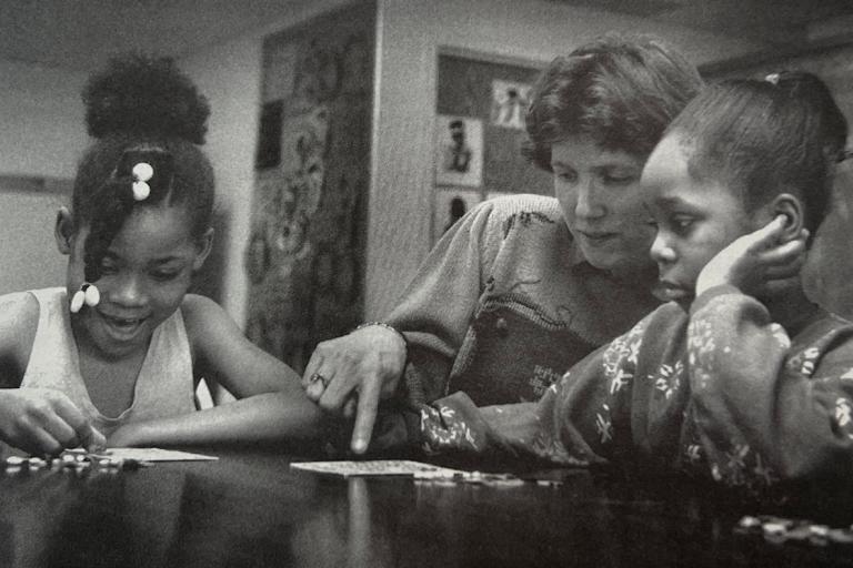 Professor Ann Masten with two elementary age children pointing at something on a table