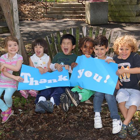 kids sitting on a bench with a thank you poster